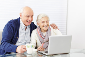 Ein älteres Paar sitzt vor einem Computer