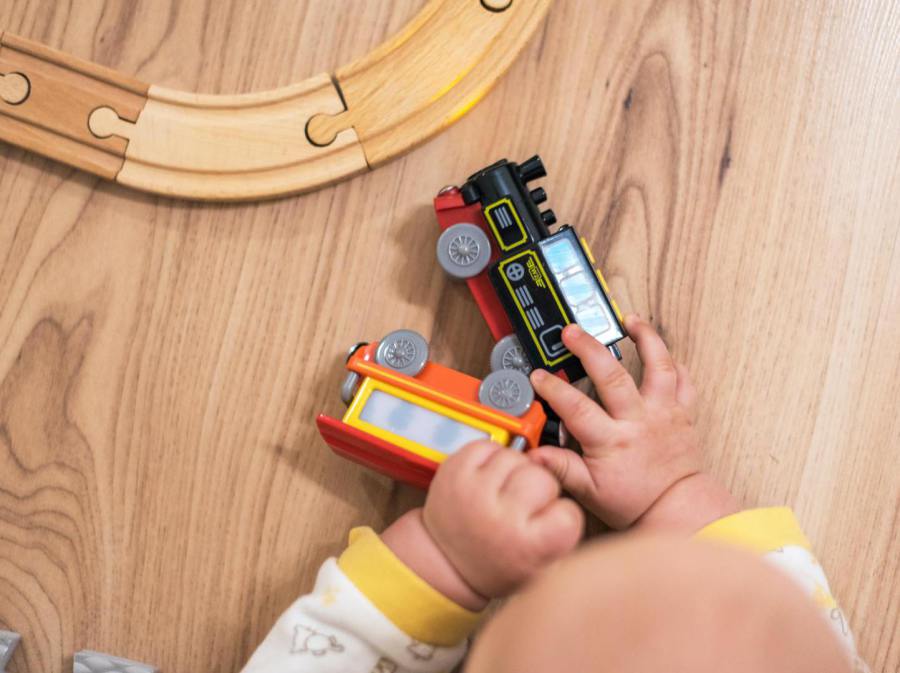 Baby spielt mit Holzeisenbahn