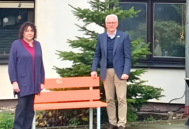 Gleichstellungsbeauftragte und Bürgermeister neben orangener Sitzbank