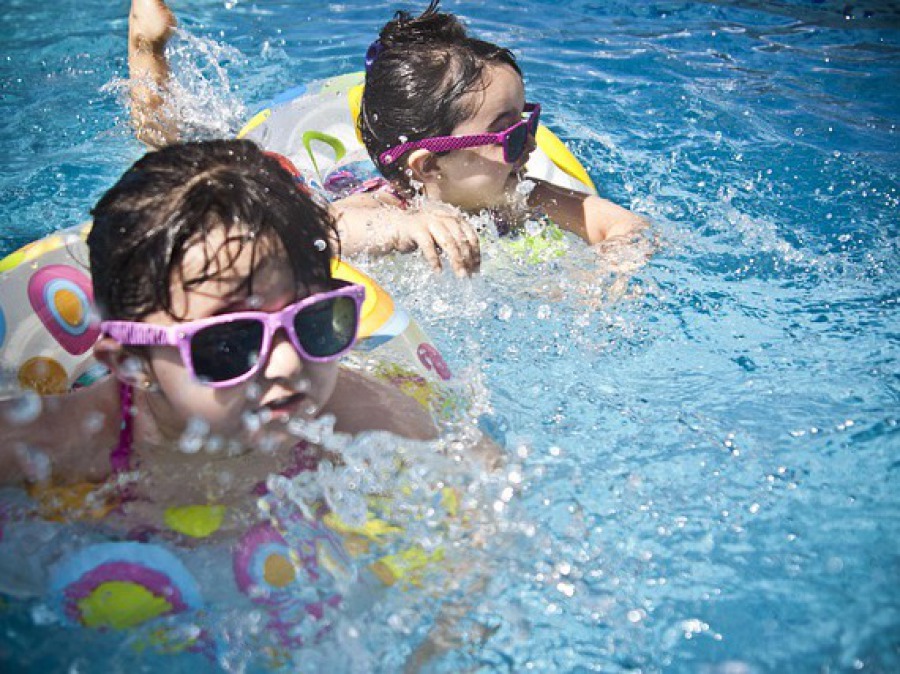 Zwei Kinder mit Schwimmreifen im Schwimmbad